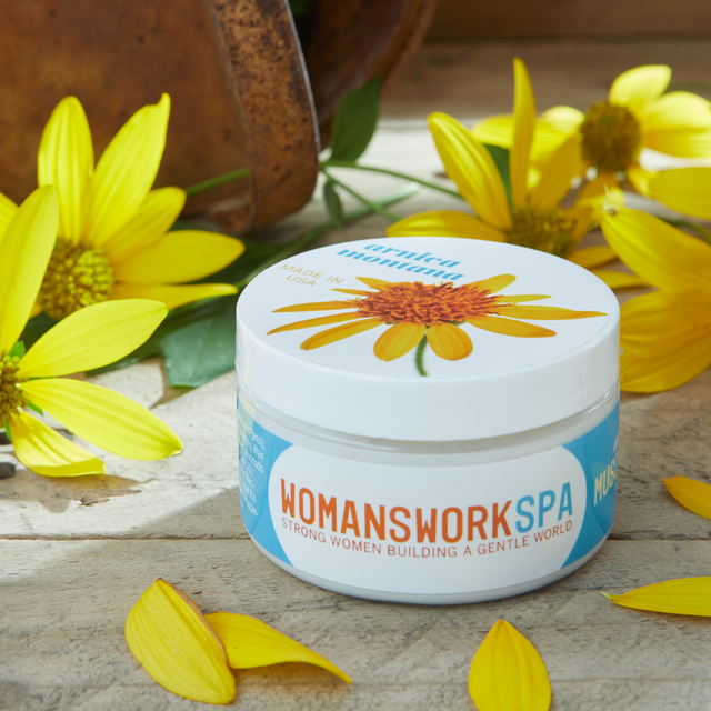 Jar of 'Womanswork Spa' product with yellow flowers on a wooden surface