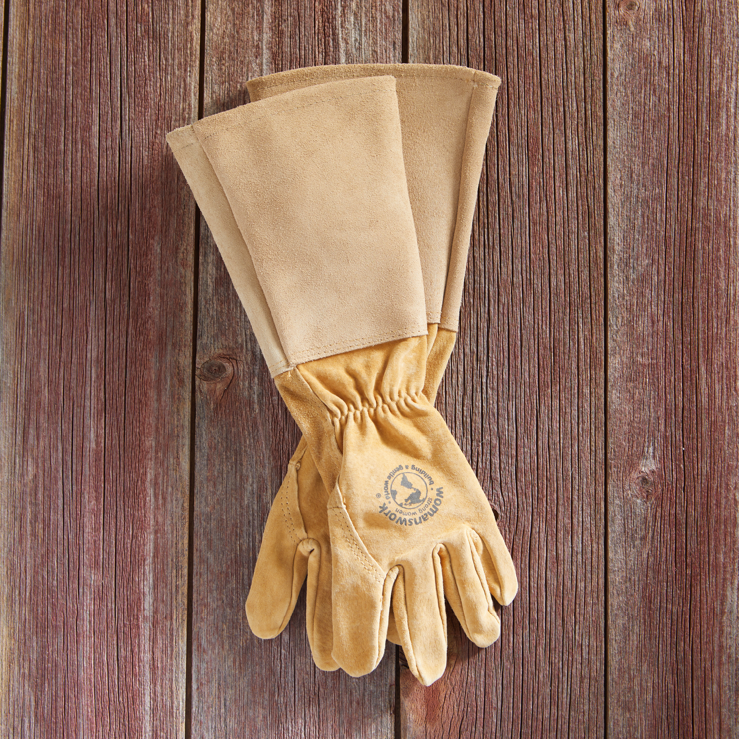 Pair of tan leather gloves on a wooden background