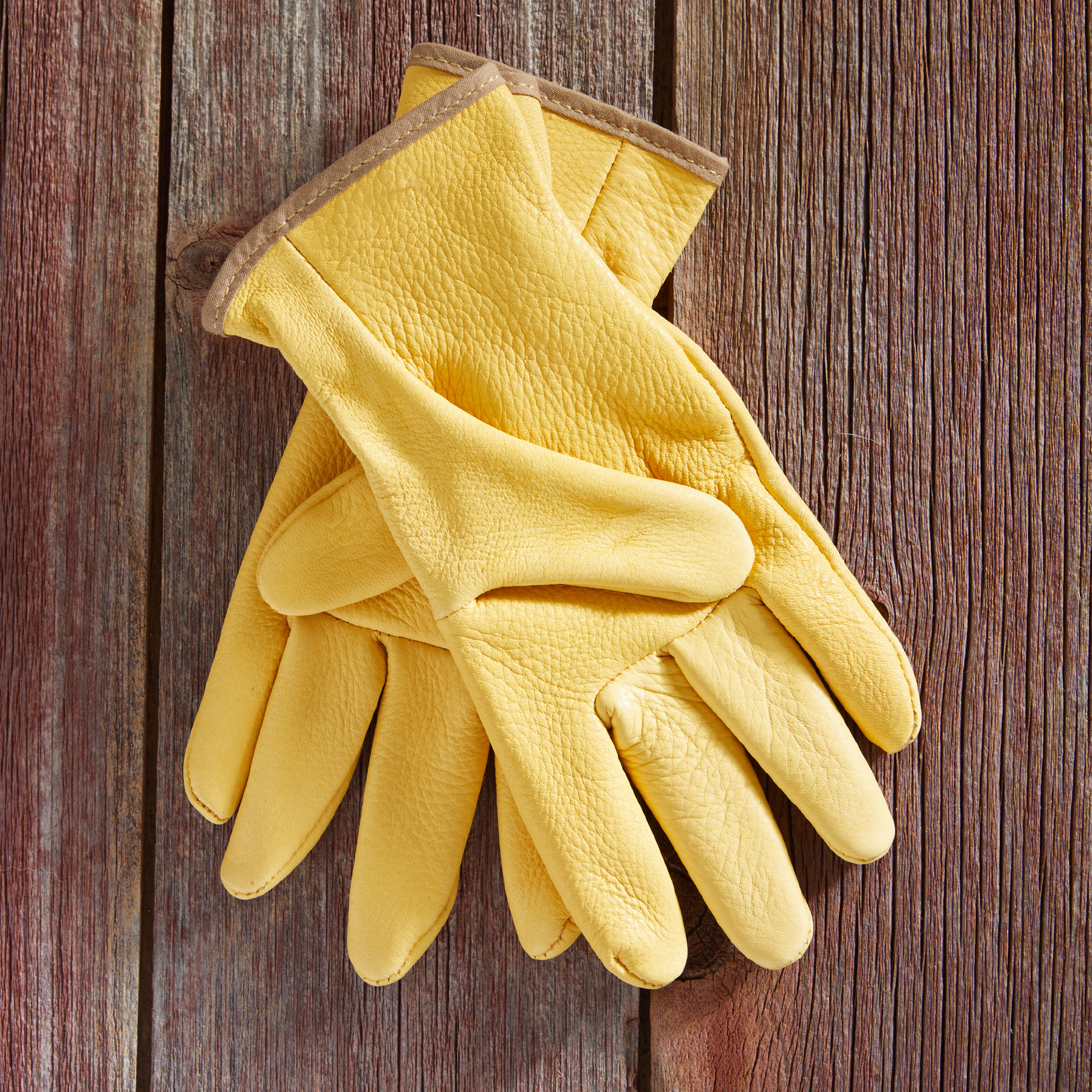 Pair of yellow gloves on a wooden surface