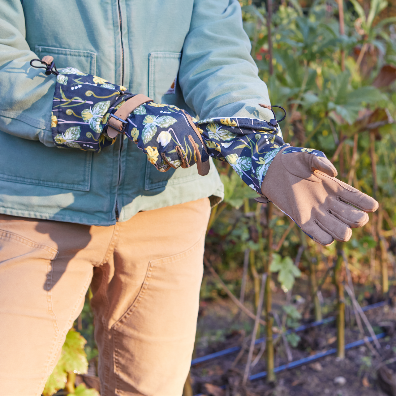 Person wearing floral gloves and a blue jacket in an outdoor setting