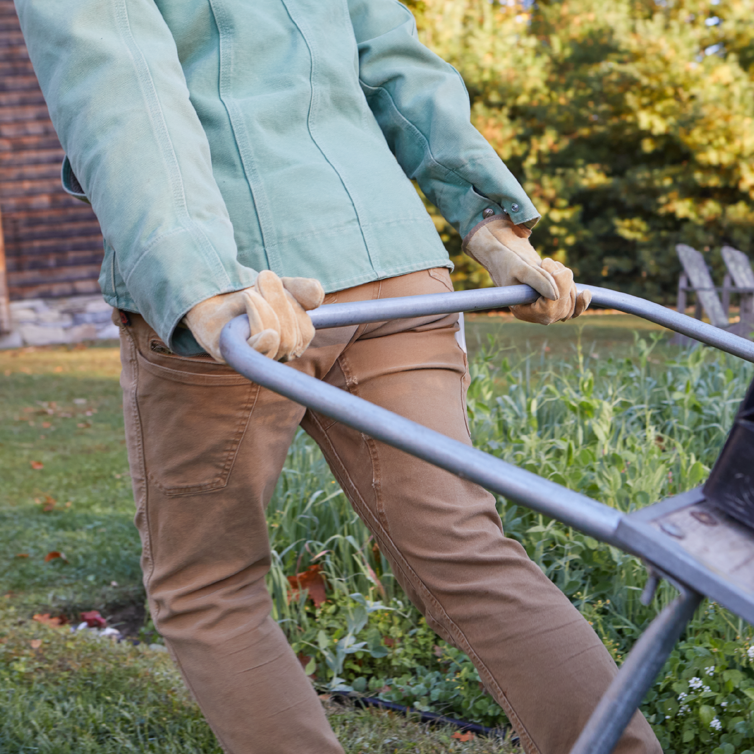 Person pushing a wheelbarrow in a garden setting