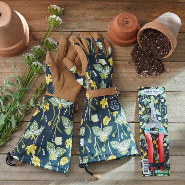 Gardening gloves with floral pattern, shears packaging, and gardening tools on a wooden surface.