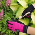 Gloves with gardening tool on green plants