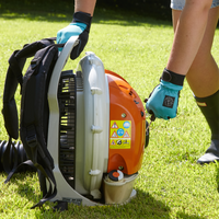 Person operating a backpack leaf blower on grass